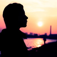 沈む夕日と女性のシルエット、夕焼け空に浮かぶ横顔の写真