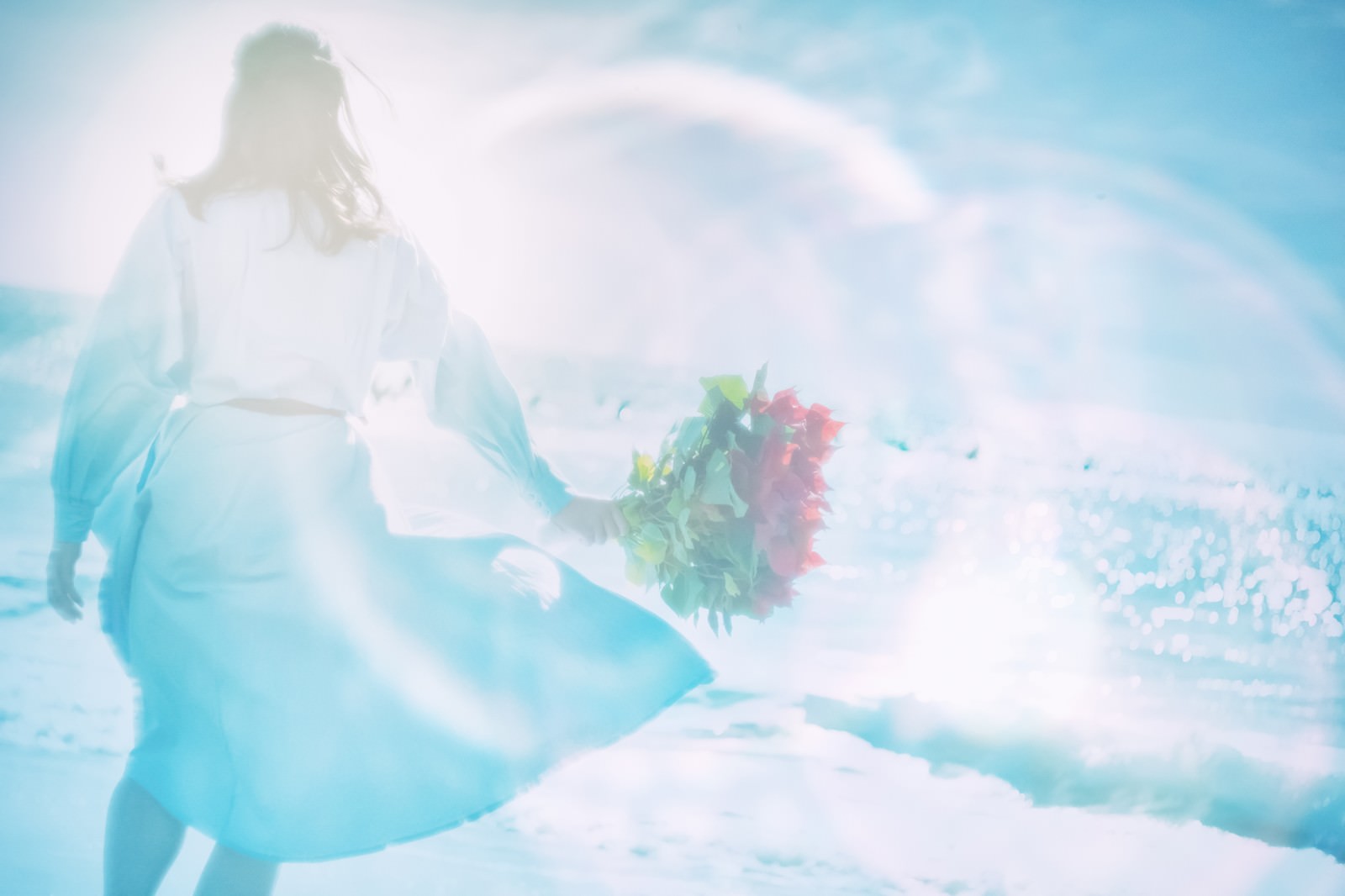 海辺で色とりどりの花束を持つ女性の後ろ姿のフォトモンタージュ
