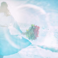 海辺で色とりどりの花束を持つ女性（フォトモンタージュ）の写真