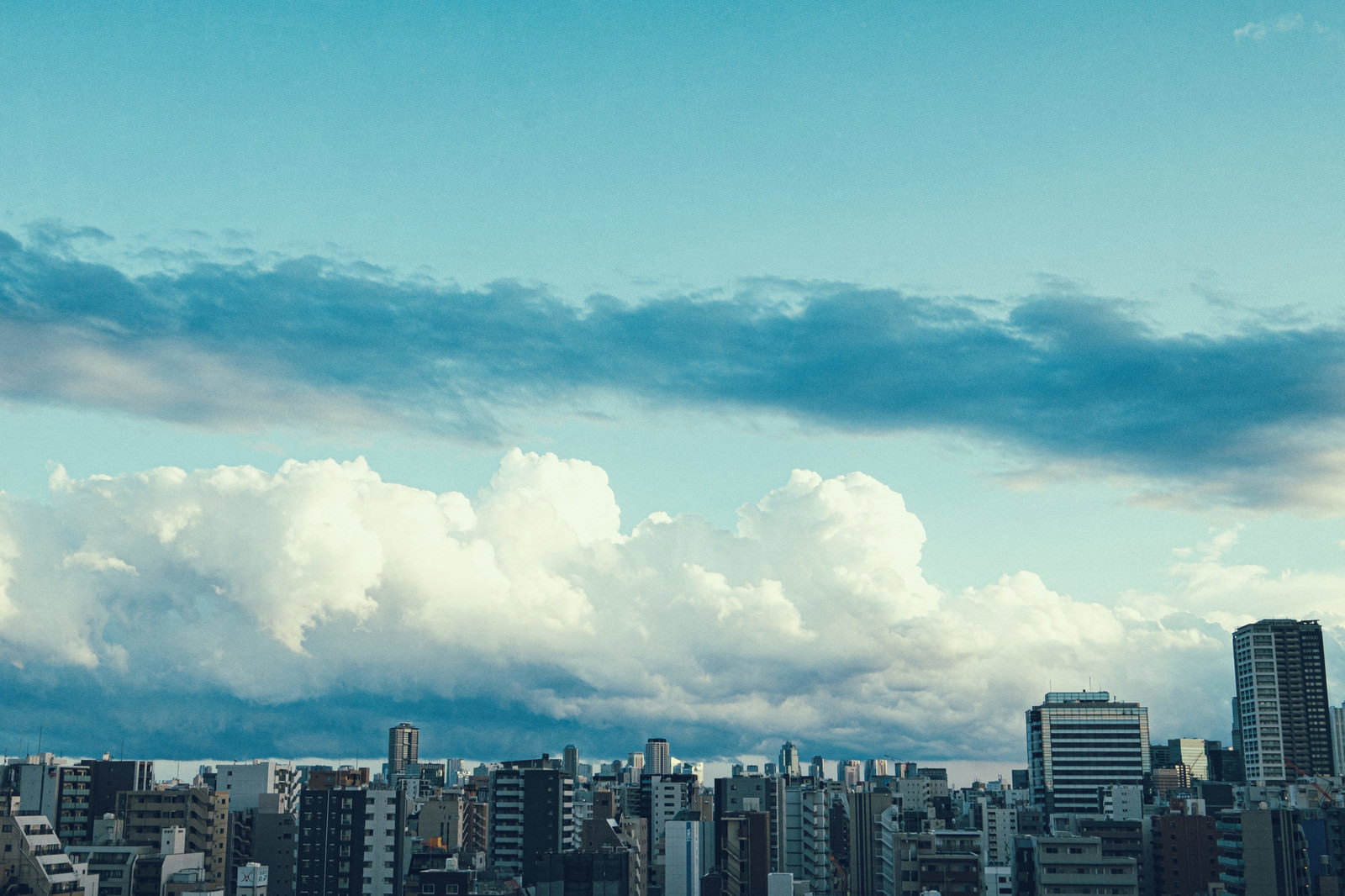 青空と白い雲の下に立ち並ぶ都会の高層マンション群