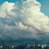 都市部の上空に立ち上る大きな雨雲と積乱雲の写真