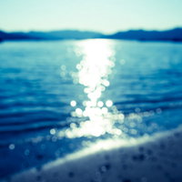 夏の海面に広がる太陽の光（ボケ）の写真