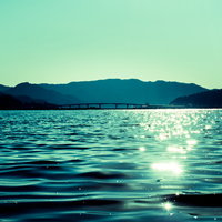 穏やかな宇佐湾に架かる橋と朝日、浜辺から見た海岸風景の写真
