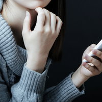 深刻な悩みをスマートフォンでネット相談する女性の写真