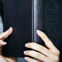 グレーのセーターを着た女性が洋書を手に取るの写真