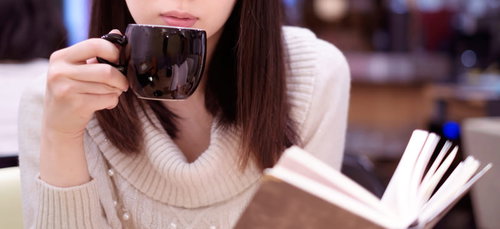 カフェでコーヒーを飲みながら読書する女性