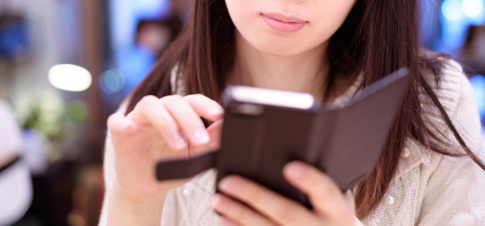 カフェでスマートフォンの画面を見ながら操作する長髪の女性
