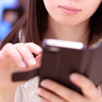 カフェでスマートフォンのアプリをチェックする女性の写真