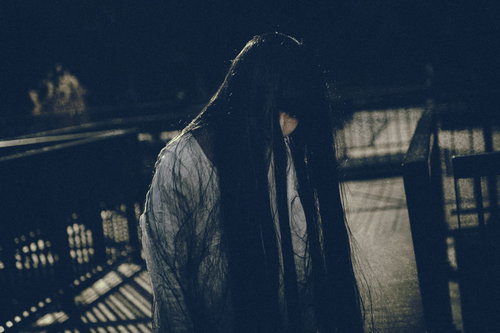 伸び切った黒髪で顔を覆う白装束の女性の不気味な姿