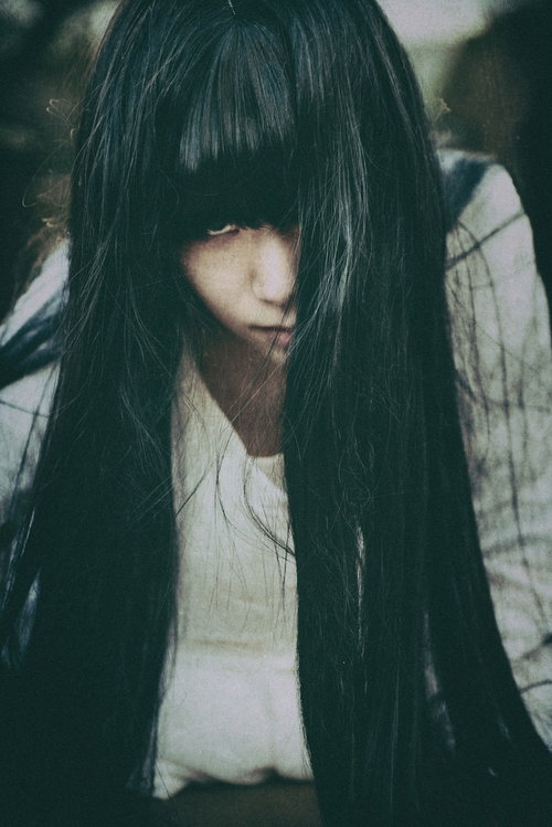 睨みつける貞子もどきが暗闇の階段に立つ