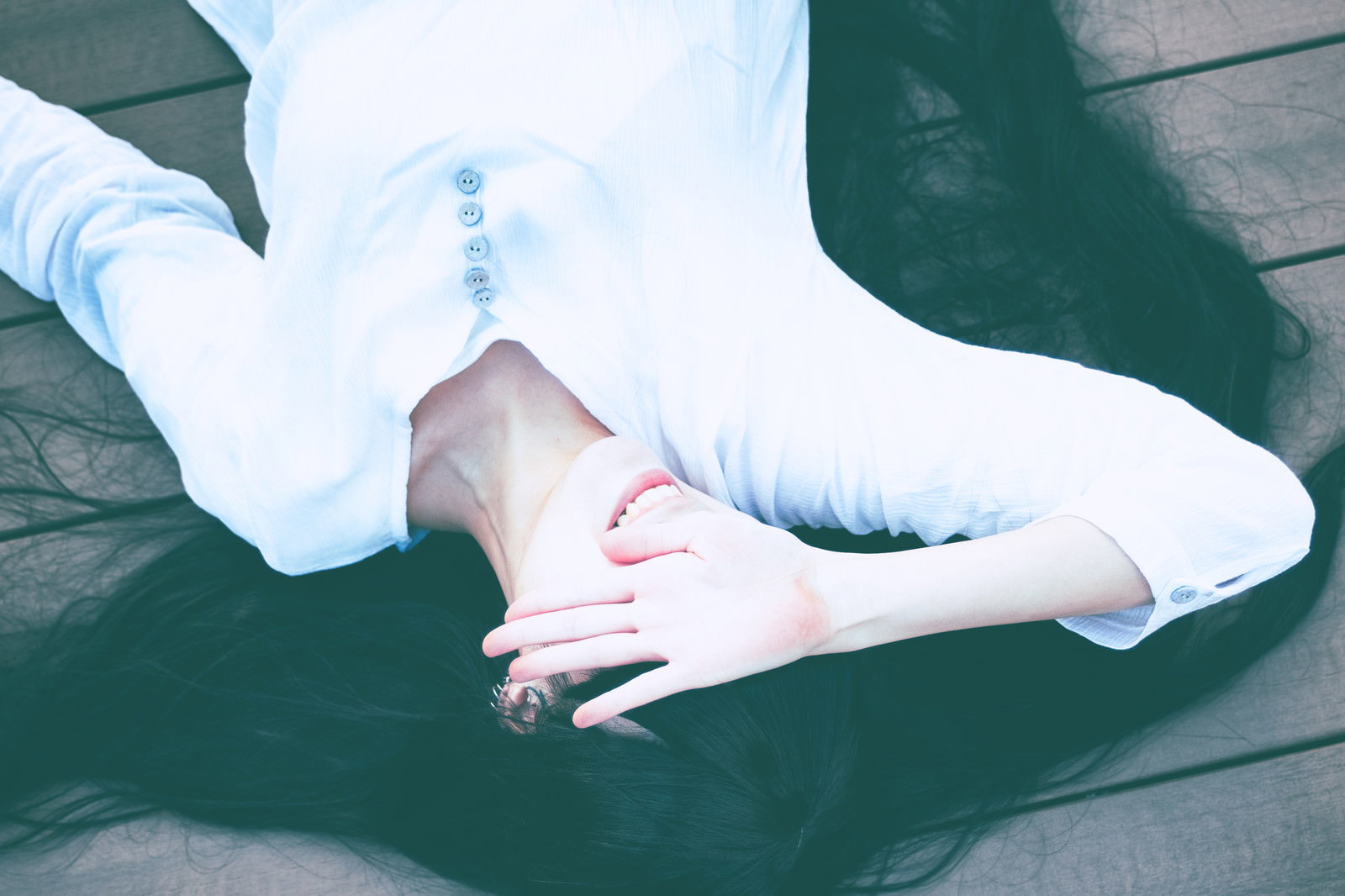 日差しを嫌がって手で顔を覆い仰向けに寝転ぶ色白の女性［モデル：緋真煉］
