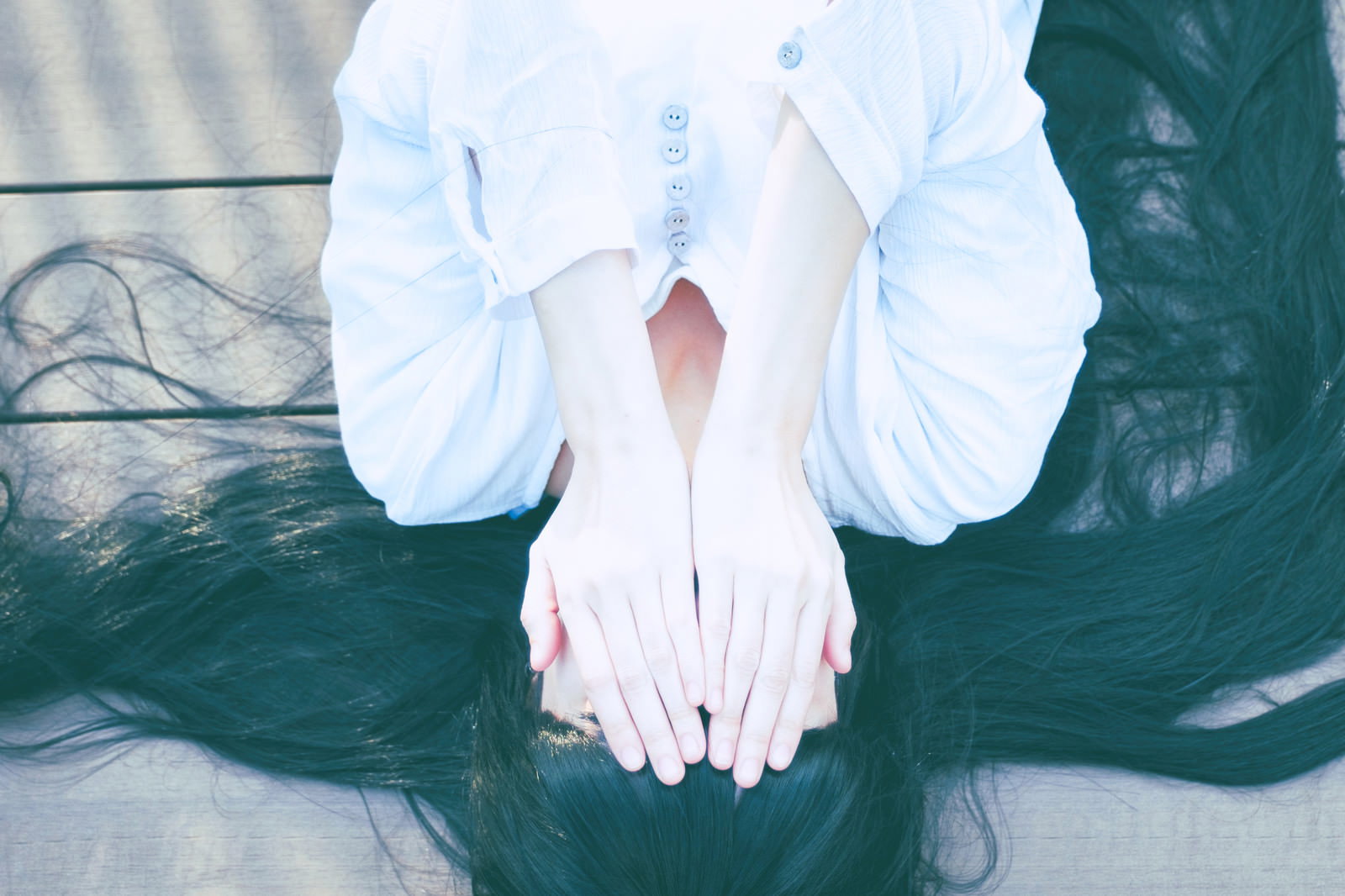 白いシャツを着た女性が両手で顔を隠している様子［モデル：緋真煉］