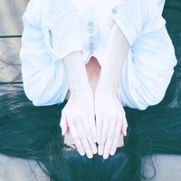 白いシャツを着て両手で顔を隠す女性の写真
