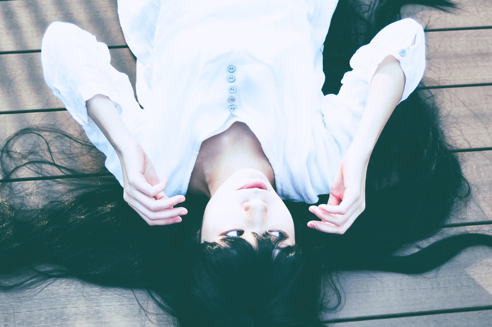 白い服を着た女性が地面に仰向けに寝転んで辺りを警戒している様子［モデル：緋真煉］