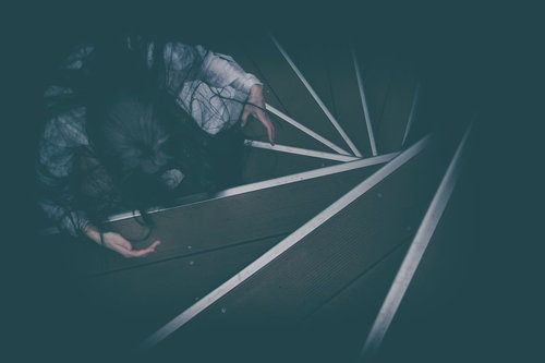 暗い螺旋階段で待機する怖がらせ役の女性の肝試し企画