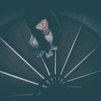 どこまでも続く螺旋階段を見上げる女性のシルエットの写真