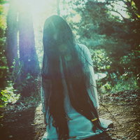 森の中で膝から崩れ落ちる女性の写真