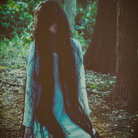 森の奥深くで膝をついて蹲る白い服の女性の恐怖の写真