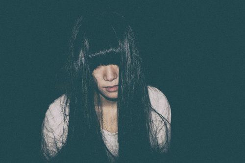 長い黒髪で顔を覆い恨み晴らします女性の怨念の姿