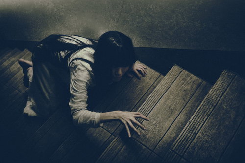 物音を立てないように薄暗い階段を上る女性