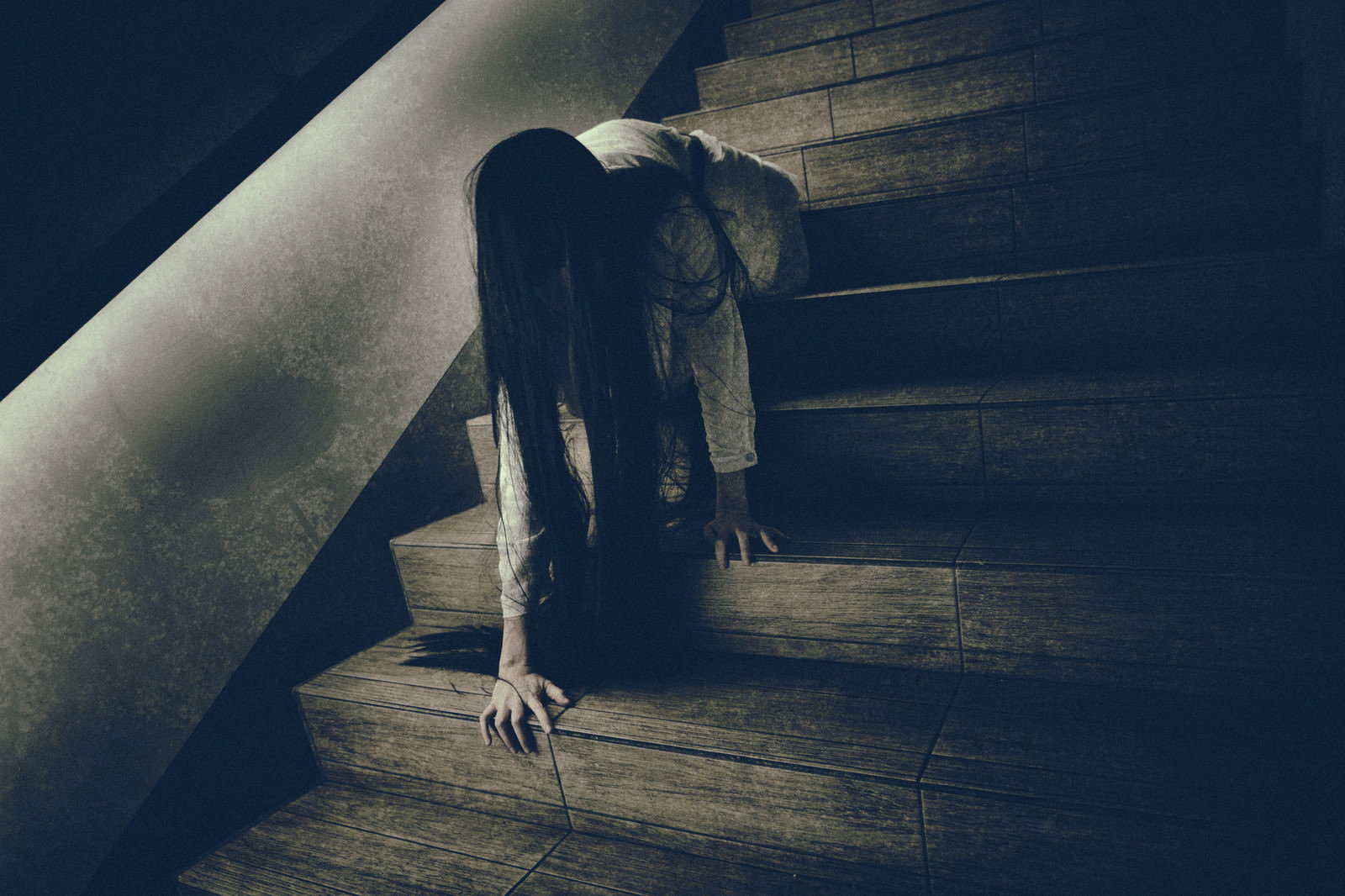 薄暗い階段に座り込み、ゆっくりと首を上げる女性［モデル：緋真煉］
