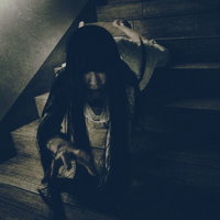 薄暗い階段を這い降りながらこちらに手を伸ばす女性の写真