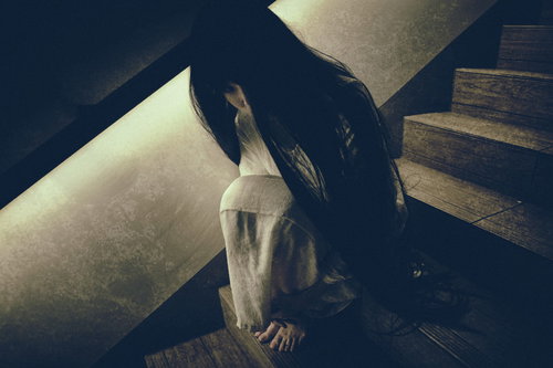 階段に蹲り恨めしそうに見上げる女性の怨念