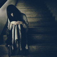 終電を逃した薄暗い階段で俯く不気味な女性の写真