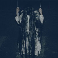 暗い背景で項垂れるブランコに座る髪の長い女性の写真