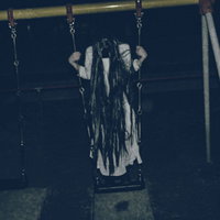 暗い公園で立ちこぎするブランコの髪の長い女性の写真