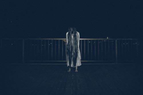 真夜中の公園で前屈みの姿勢をとる裸足の女性