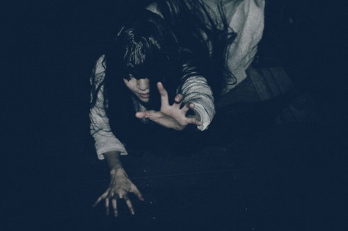 這い蹲りながら恨めしそうに掴みかかろうとする女性