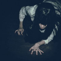 暗闇で這いつくばる白い衣装の女性のホラーの写真