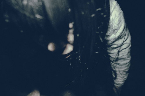 薄暗い空間で睨みつける不気味な女性の顔と長い髪