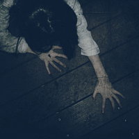 暗闇で爪を立てて這い蹲る長い髪の女性の恐怖シーンの写真