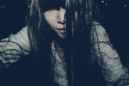 痛んだ長い黒髪で顔を覆う女性の幽霊