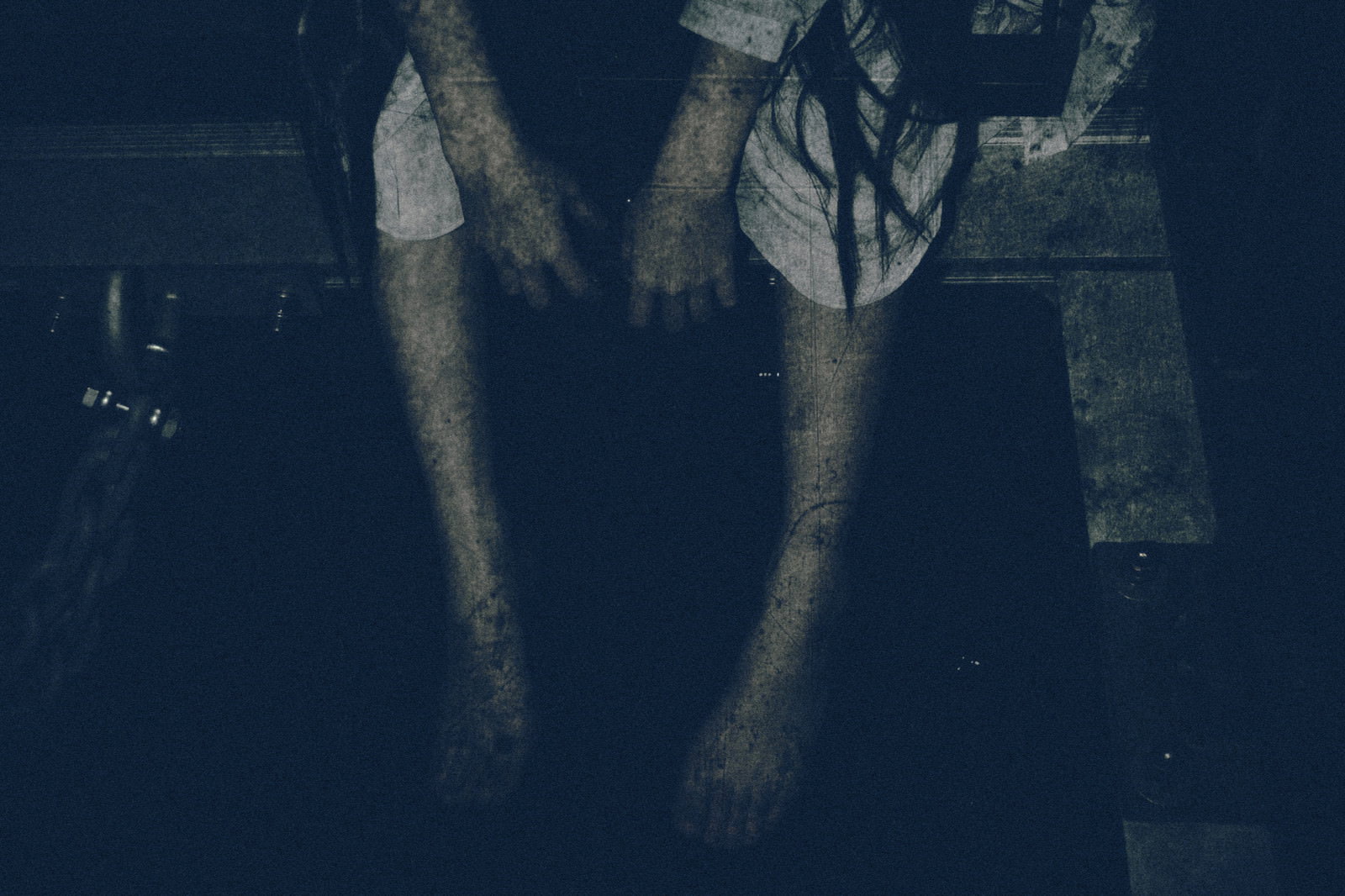 暗い場所で座り込み手足をぶら下げる女性のホラーな雰囲気の写真［モデル：緋真煉］