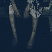 暗い場所で座り込んで手足をぶら下げる女性の姿の写真