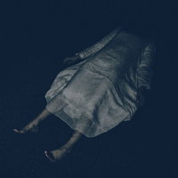 白いワンピースを着て薄暗い空間に横たわる女性の恐怖シーンの写真