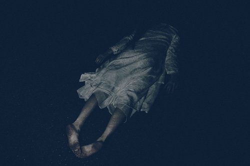 暗闇の中で髪を垂らし項垂れる不気味な女