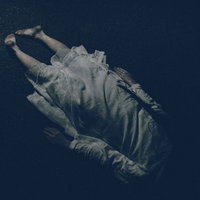 路上に横たわる白いワンピースの女性の裸足の写真