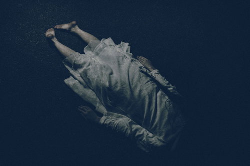 路上に横たわる白いワンピースの女性の裸足