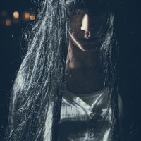 伸びた髪の間から怨めしそうに見つめるストーカー怖い女性の写真