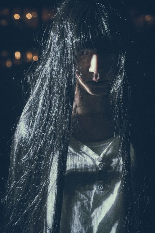 伸びた髪の間から怨めしそうに見つめるストーカー怖い女性