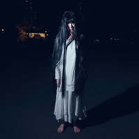 だらんと伸ばした長い髪でじっと立つ幽霊女性の写真