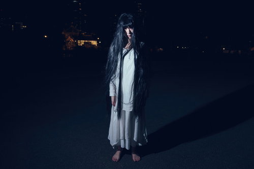 だらんと伸ばした長い髪でじっと立つ幽霊女性