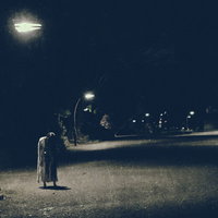 薄暗い街灯下に立つ女性の怨念と不気味な夜道の恐怖の写真