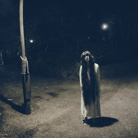 真夜中の公園の照明の下で仁王立ちする女性の写真