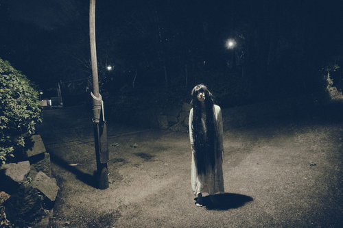 真夜中の公園の照明の下で仁王立ちする女性