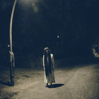 真夜中の公園を裸足で徘徊する女性のシルエットの写真